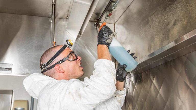 Professional technician cleaning commercial kitchen ventilation canopy system